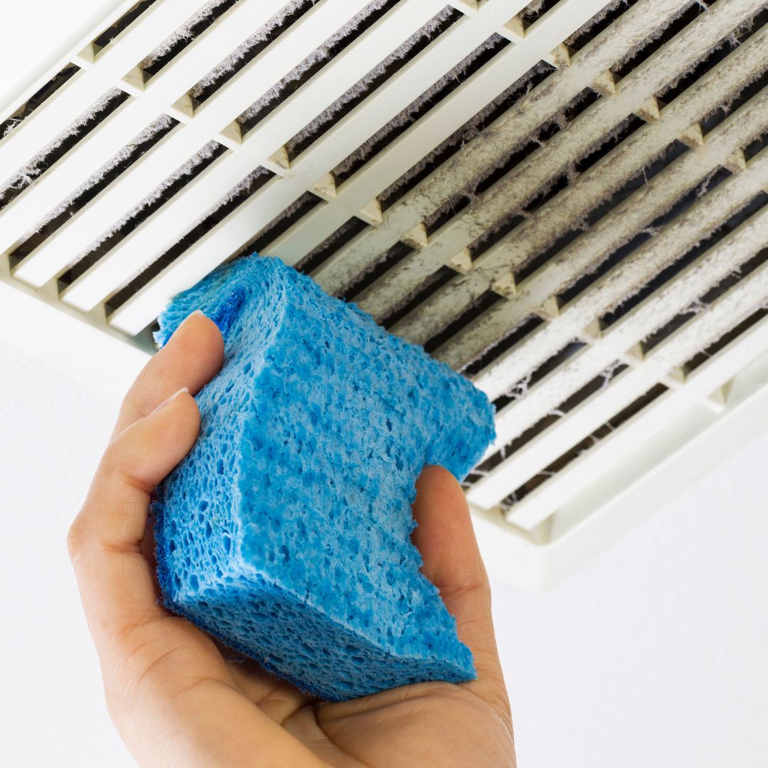 person wiping dust from a vent